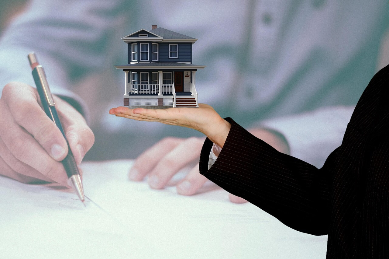 Concept image of leveraged real estate investment showing a house model in hand, representing comparison with ETF long-term investing